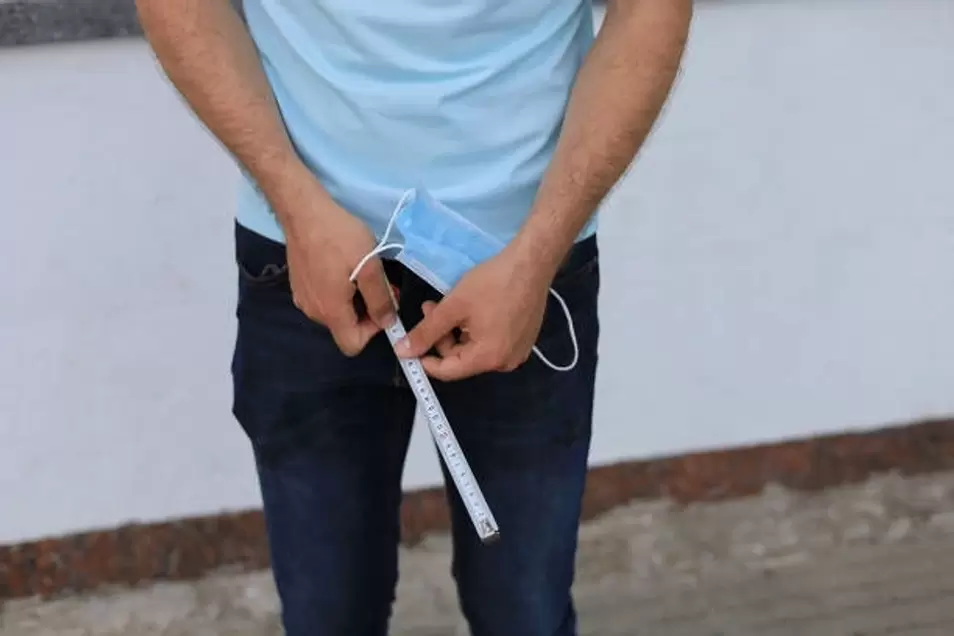 a man measures his penis before enlarging